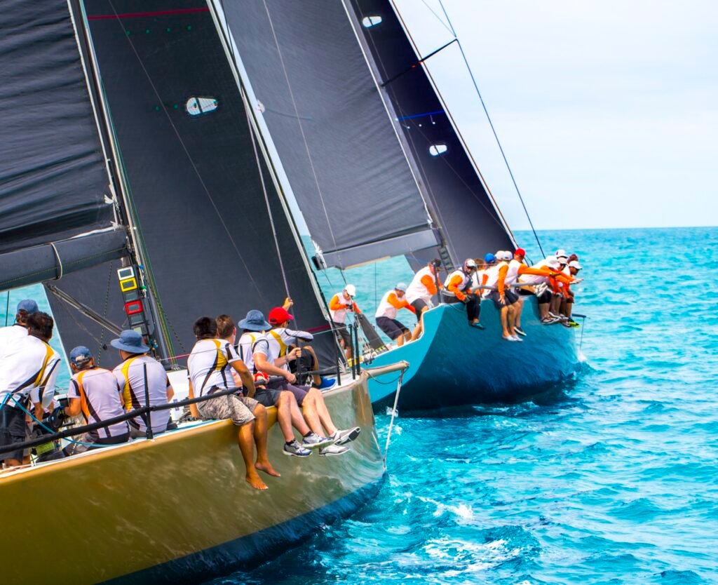 Two racing sailboat crews hiking out side by side during a regatta