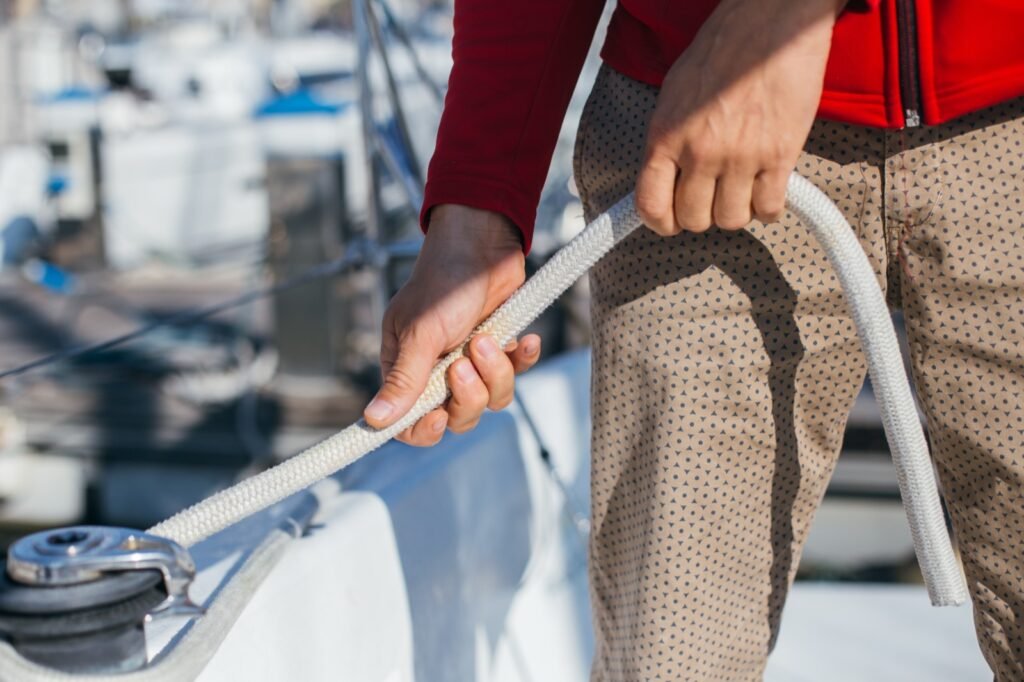 Sailor tensioning a line on a sailboat winch